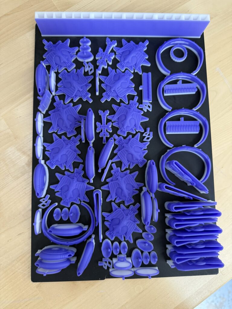 Castable resin jewelry casting patterns 3D printed at eCadCam in Los Angeles, including rings, bangles, pendants and crosses on a build plate